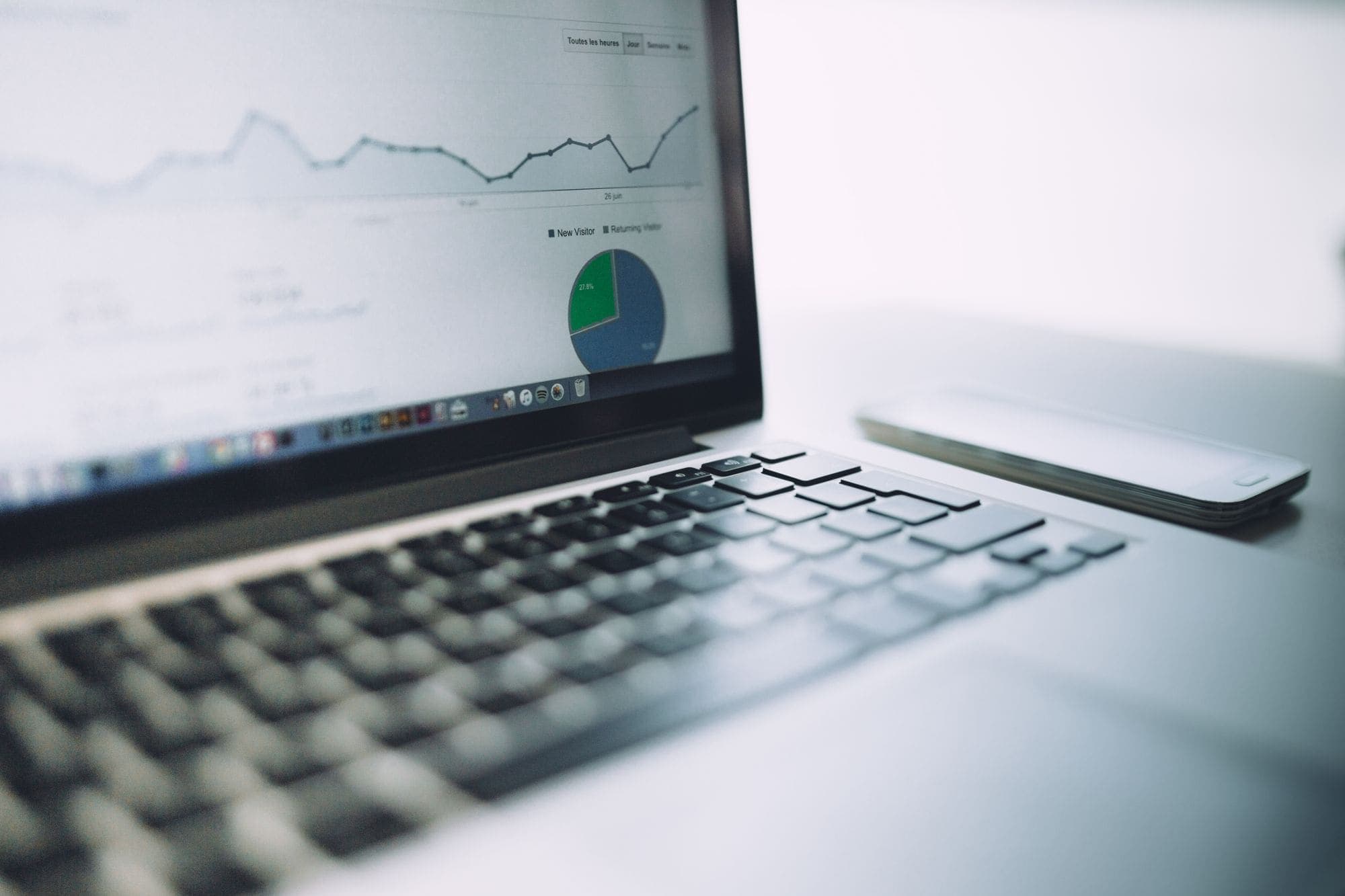 A laptop showing an analytics dashboard with charts on a bright desk